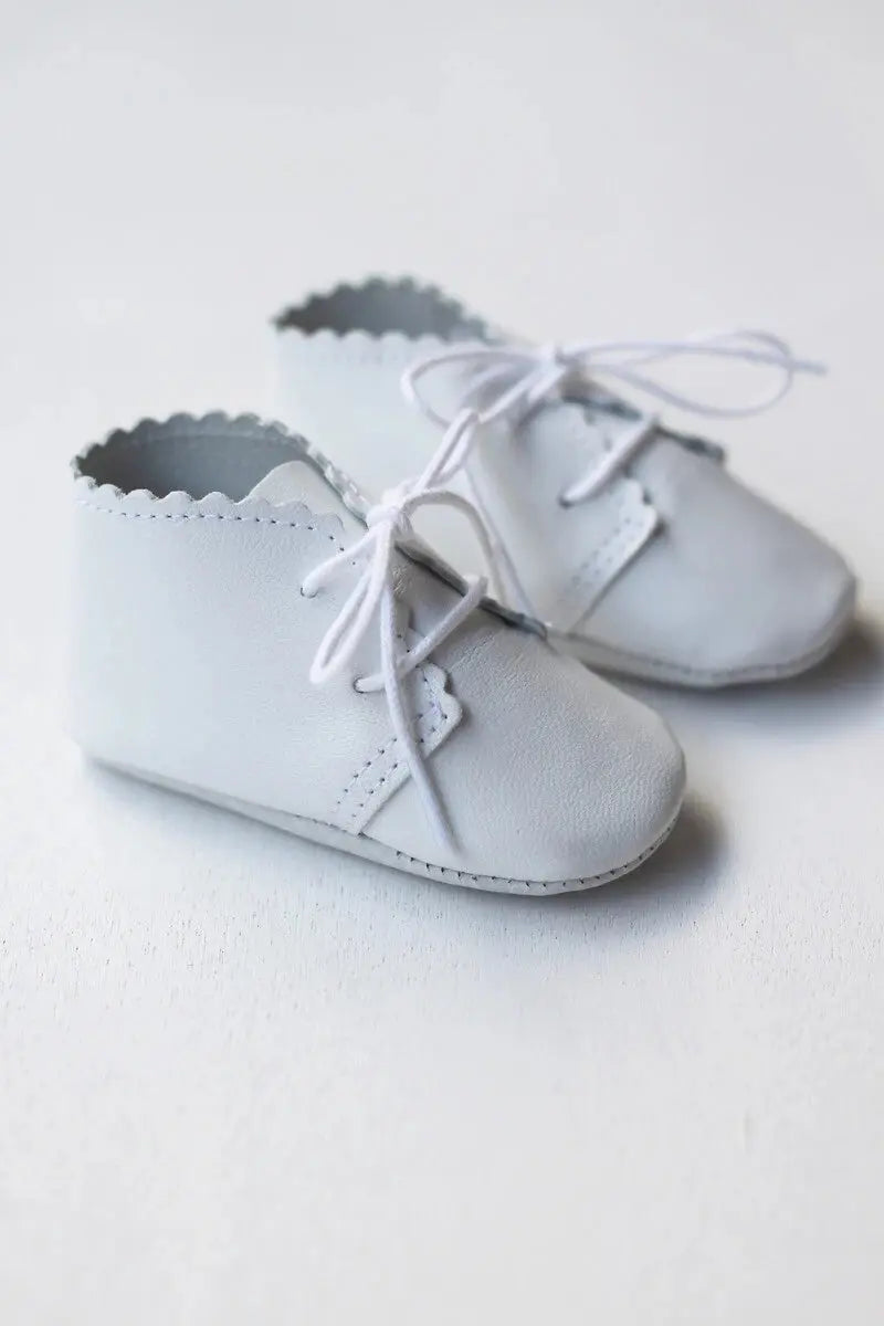 Chaussons montants bébé fille ou garçon en cuir souple blanc. Idéal pour baptême. Boutique Fil de Légende à Paris, Neuilly-sur-Seine. Photo des chaussons vus de côté.