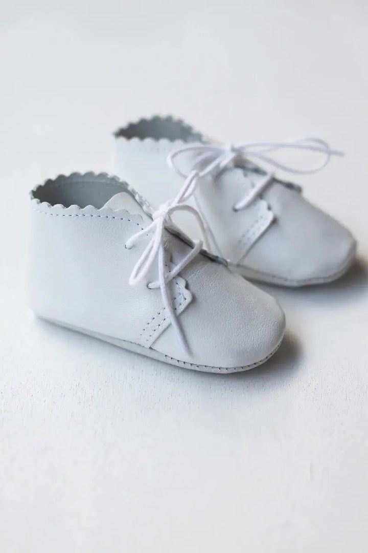 Chaussons montants bébé fille ou garçon en cuir souple blanc. Idéal pour baptême. Boutique Fil de Légende à Paris, Neuilly-sur-Seine. Photo des chaussons vus de côté.