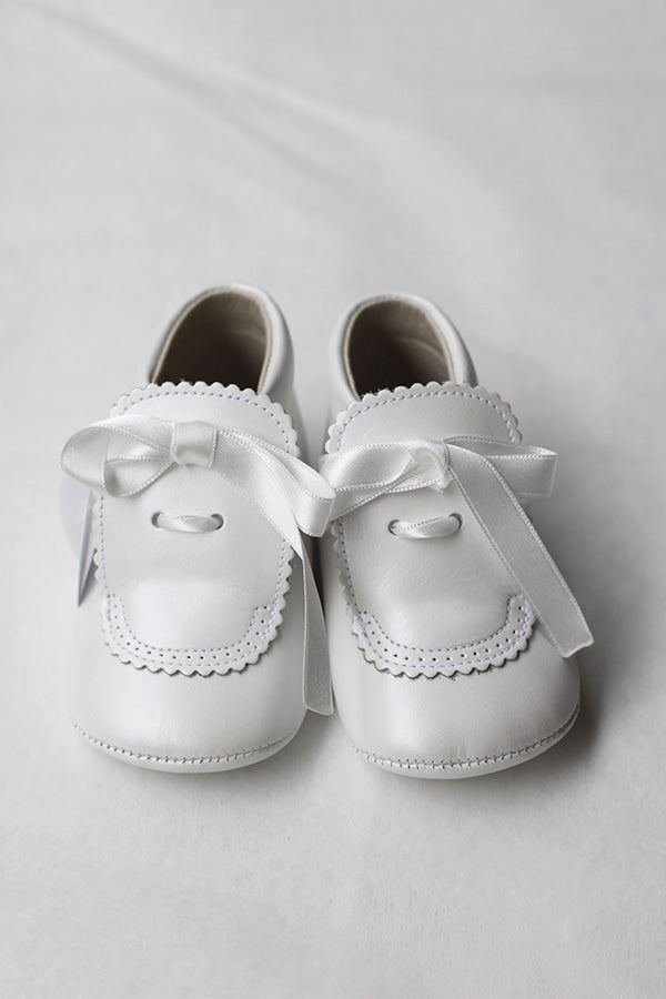 Chaussons montants bébé fille pour  cérémonie ou baptême - En cuir blanc cassé avec une décoration raffinée et un joli nœud en satin -  Magasin Fil de Légende Paris, Neuilly-sur-Seine.