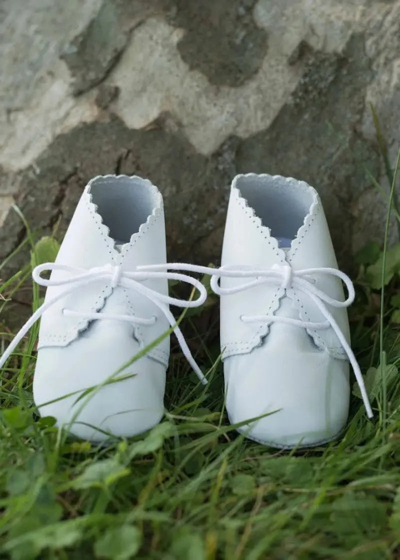 Chaussons montants bébé fille ou garçon en cuir souple blanc. Idéal pour baptême. Photo des chaussons en extérieur.