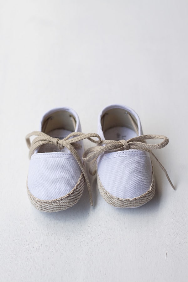 Chaussons espadrilles bébé pour cérémonie et baptême en toile blanche et lacets beiges. Vue de face.