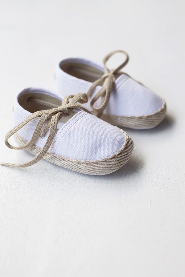 Chaussons espadrilles bébé pour cérémonie et baptême en toile blanche et lacets beiges. Vue de côté.