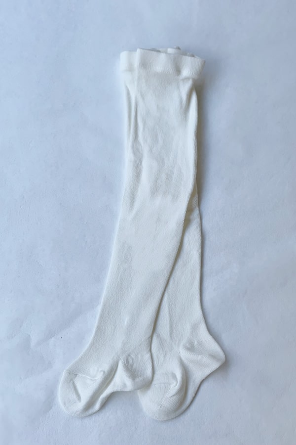 Collant épais en coton chaud blanc cassé pour bébé fille. Idéal à porter avec une robe de cérémonie bébé blanc cassé. Photo du collant vu de côté.