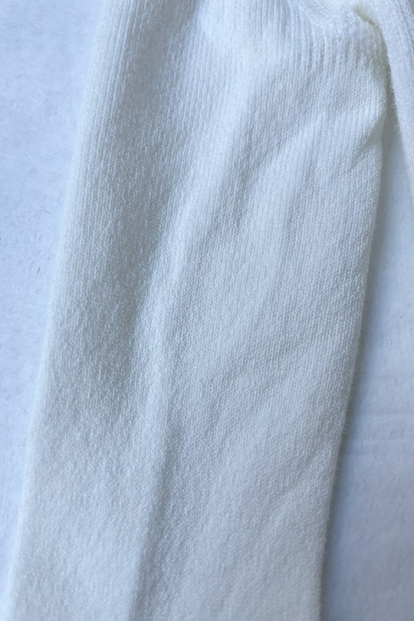 Collant épais en coton chaud blanc cassé pour bébé fille. Idéal à porter avec une robe de cérémonie bébé blanc cassé. Photo de la texture du collant.