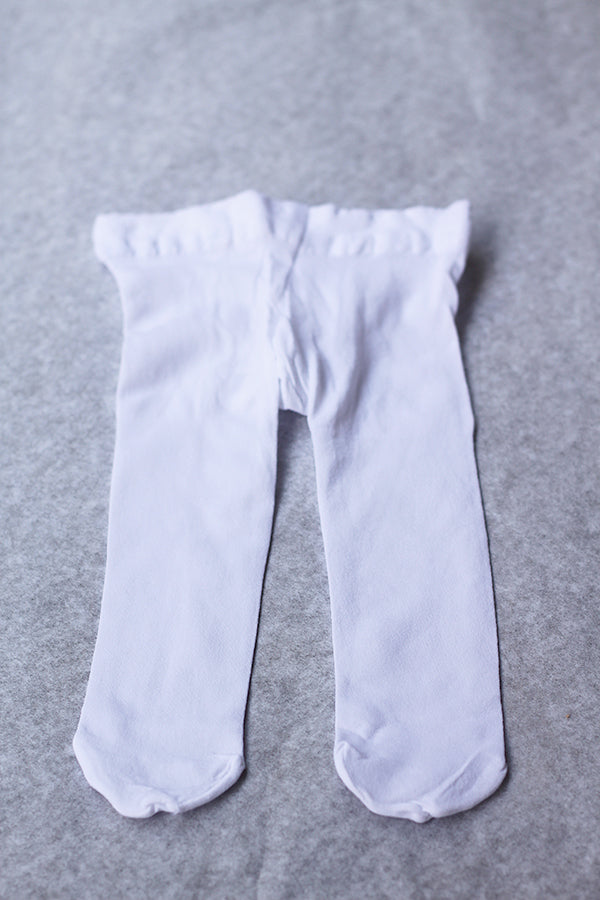 Collant fin blanc pour bébé fille, de type collant de danse. Idéal à porter avec une robe de cérémonie. Boutique Fil de Légende à Paris, Neuilly-sur-Seine.