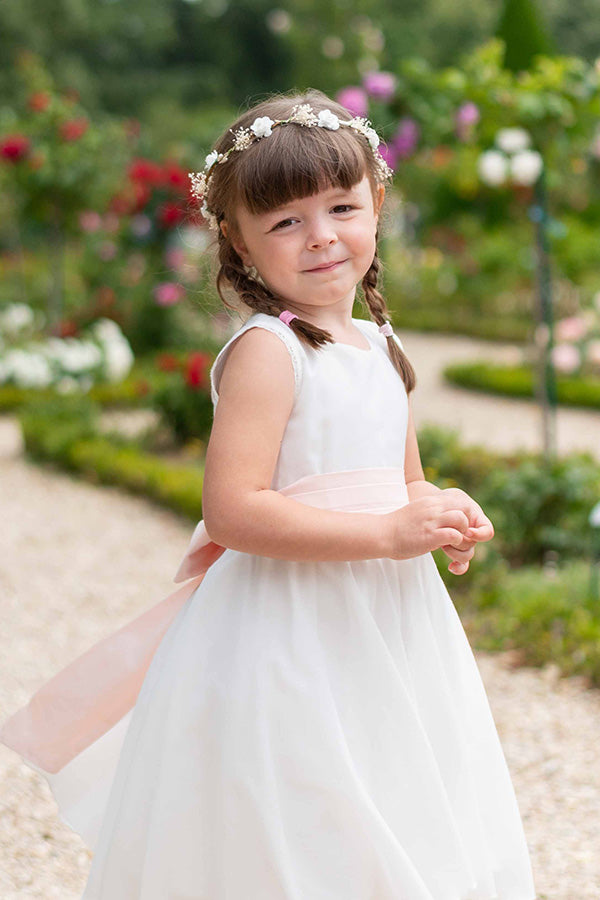 Couronne artificielle de petites fleurs blanches et gypsophile à porter avec une robe de cérémonie pour enfants. Parfait pour sublimer une coiffure de petite fille. Photo de la couronne portée par une petite fille.