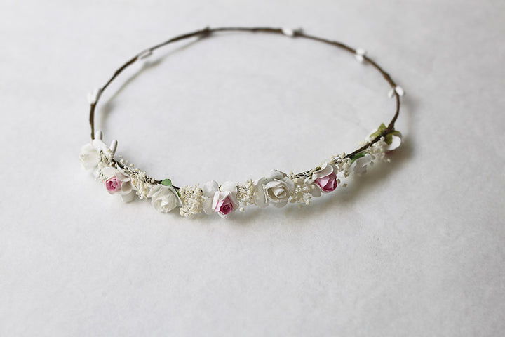 Couronne de fleurs artificielles blanches et roses à porter avec une robe de cérémonie pour enfant. Parfait pour sublimer une coiffure de petite fille. Photo de la couronne posée à plat.