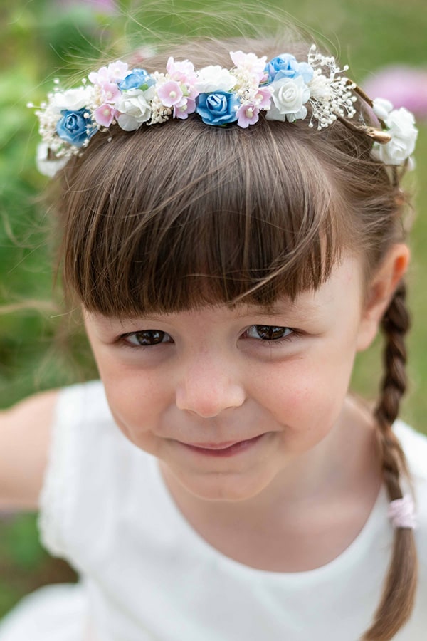 Couronne de fleurs artificielles blanches, bleues et roses pour petites filles à porter avec une robe de cérémonie pour enfants. Parfait pour sublimer une coiffure. Photo de la couronne vue de face.
