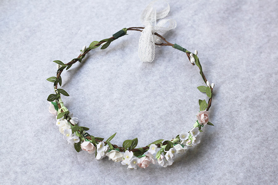 Couronne de fleurs artificielles blanche et rose pâle pour petites filles à porter pour accessoiriser une robe de cérémonie pour enfant et sublimer une coiffure.