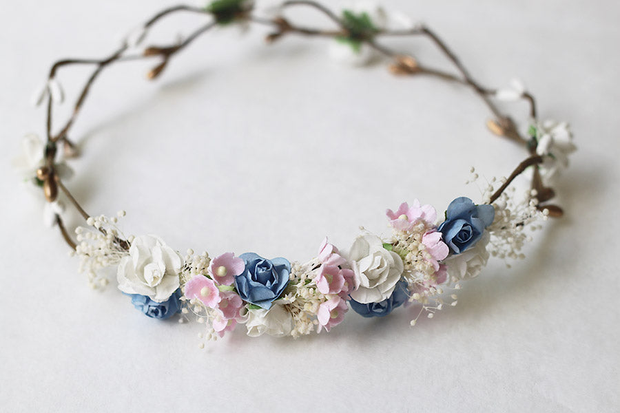 Couronne de fleurs artificielles blanches, bleues et roses pour petites filles à porter avec une robe de cérémonie pour enfants. Parfait pour sublimer une coiffure. Photo de la couronne posée à plat.