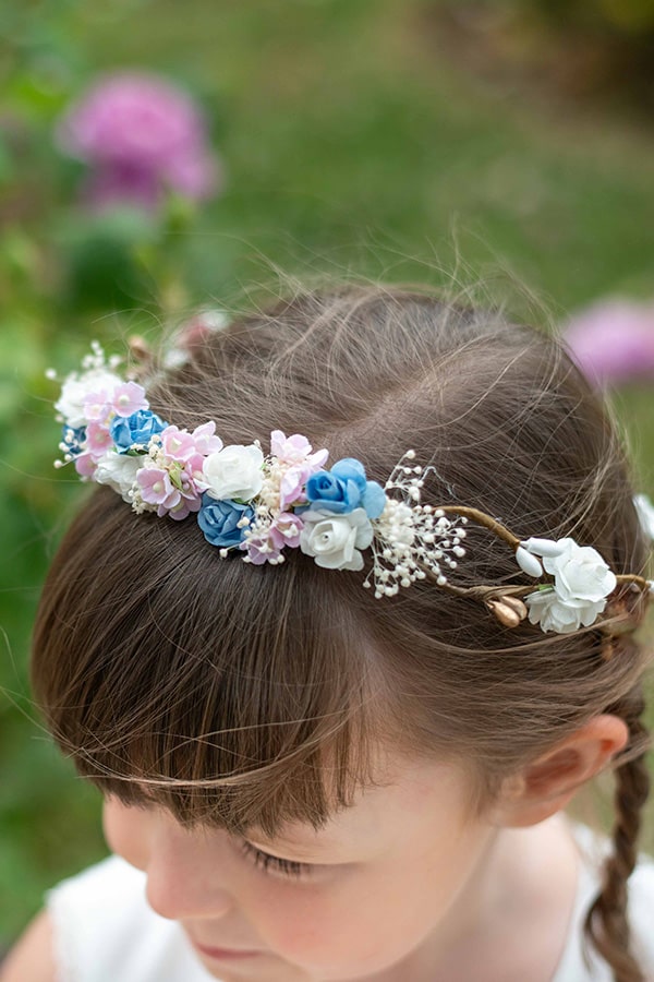 Couronne de fleurs artificielles blanches, bleues et roses pour petites filles à porter avec une robe de cérémonie pour enfants. Parfait pour sublimer une coiffure. Photo de la couronne portée par une petite fille.