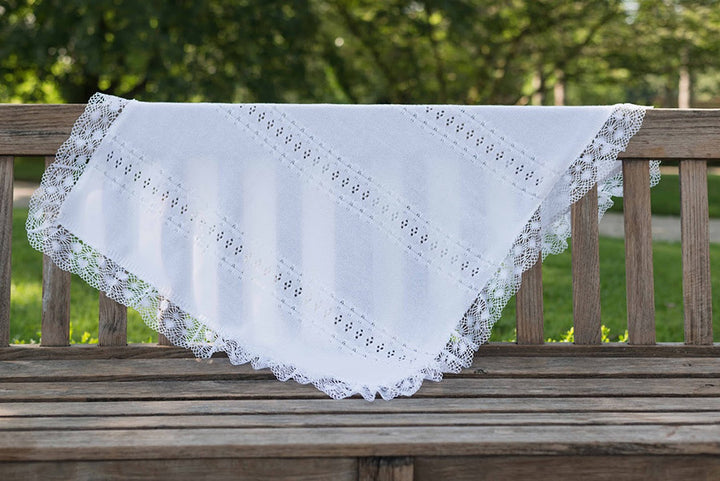 Couverture tricotée pour bébé en coton ajouré, bordée d'un large galon de dentelle de coton. Idéal pour baptême. Photo vue de loin.