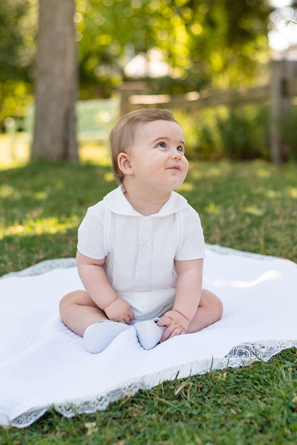 Ensemble cérémonie baptême bébé garçon avec corsage manches courtes et bloomer blanc. Modèle Anatole par Fil de Légende. Photo de l'ensemble porté par un bébé allongé assis.