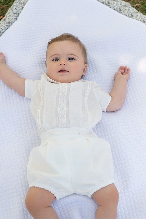 Ensemble cérémonie baptême bébé garçon avec corsage manches courtes et bloomer blanc. Modèle Anatole par Fil de Légende. Photo de l'ensemble porté par un bébé allongé.