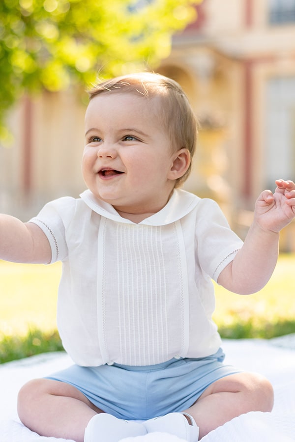 Ensemble cérémonie bébé garçon avec chemise de cérémonie manches courtes blanches et short bleu ciel. Modèle Clément, Fil de Légende. Photo de l'ensemble cérémonie bébé porté par un bébé garçon assis.