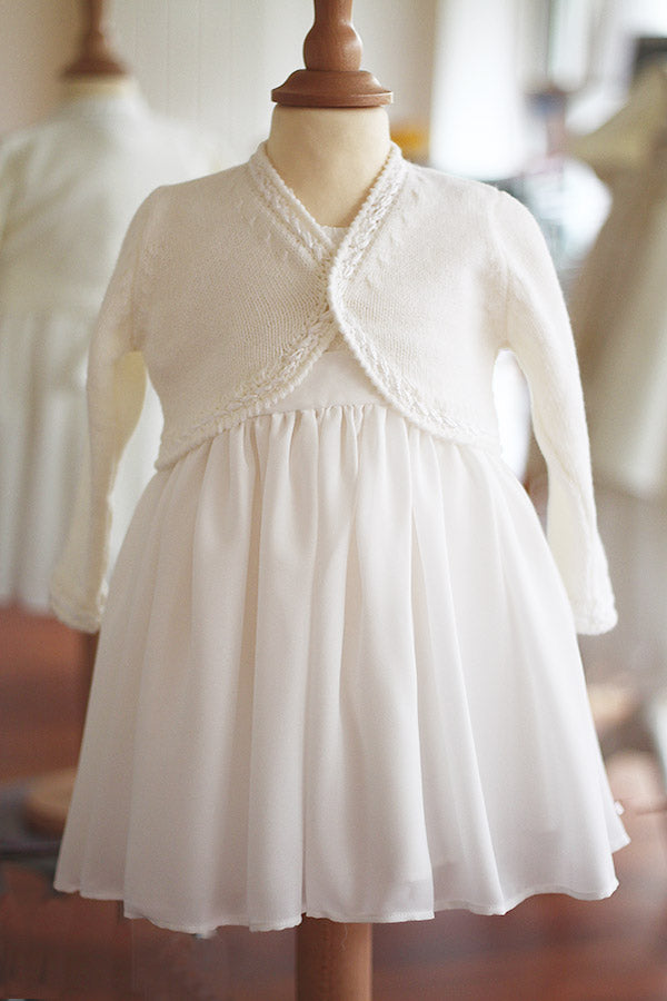Gilet boléro pour bébé fille en laine blanc cassé. A porter avec une robe de cérémonie bébé. Photo du boléro boutonné.