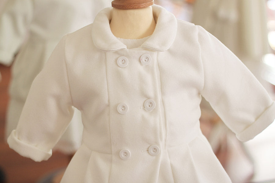 Cape de baptême automne hiver pour fille ou garçon en Mouflon blanc cassé doublé polaire. Fermeture avec boutons. Création française Fil de Légende.  Photo du haut du manteau.