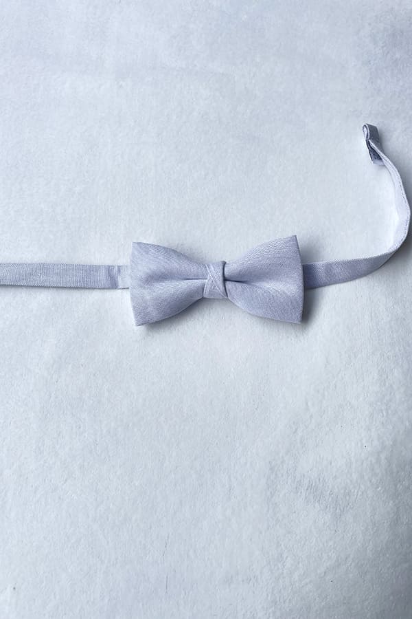 Nœud papillon pour petit garçon en coton gris perle. Idéal à porter pour une cérémonie. Photo de l'attache du nœud papillon.