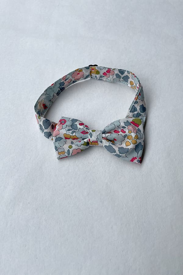 Nœud papillon pour petit garçon en coton Liberty avec fleurs de couleurs bleu gris, rouge et rose. idéal à porter pour un cortège de mariage. Boutique Fil de Légende Paris, Neuilly-sur-Seine.