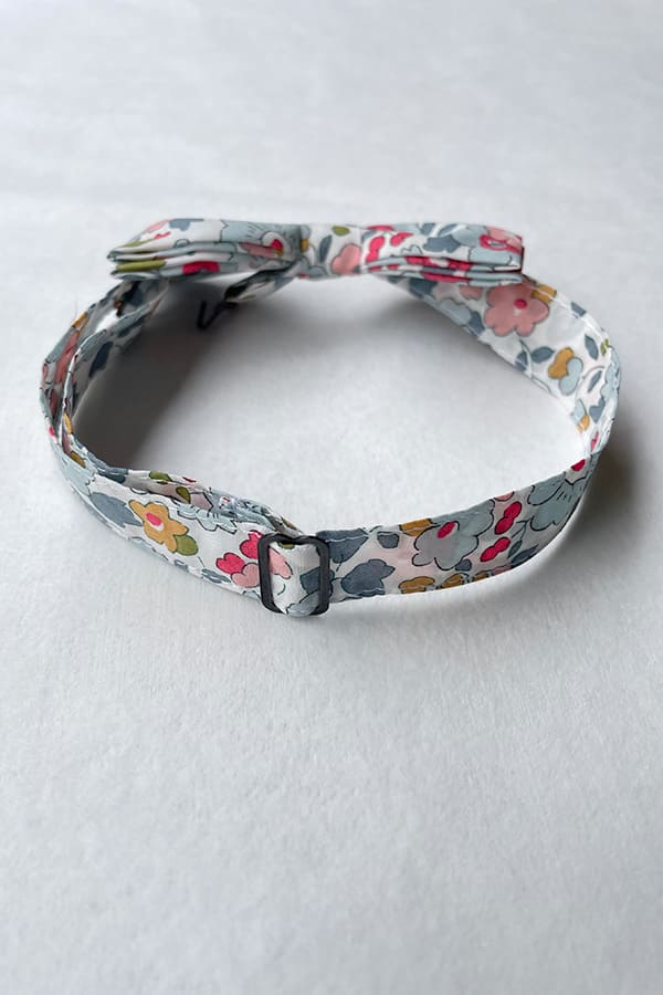 Nœud papillon pour petit garçon en coton Liberty avec fleurs de couleurs bleu gris, rouge et rose. idéal à porter pour un cortège de mariage. Photo du nœud papillon vu de dos.