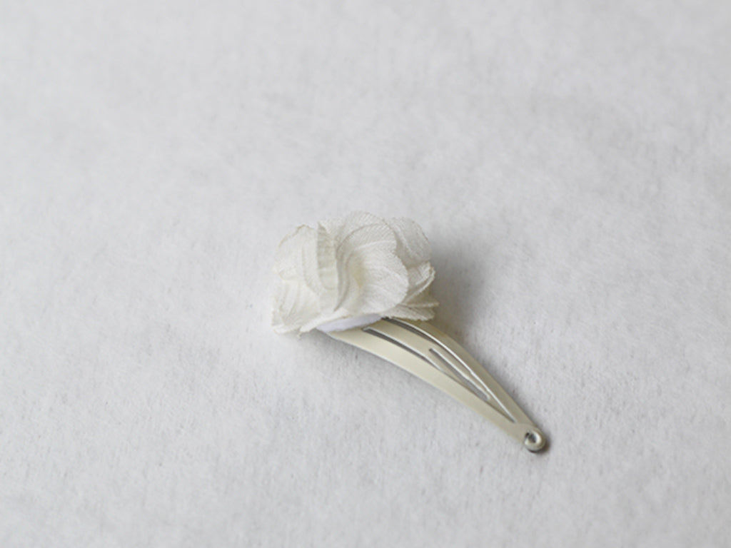 Pince cheveux bébé fille avec fleur en tissu blanc cassé. Parfait pour sublimer la coiffure d'un enfant à l'occasion d'une cérémonie. Photo de la pince cheveux vue de côté.