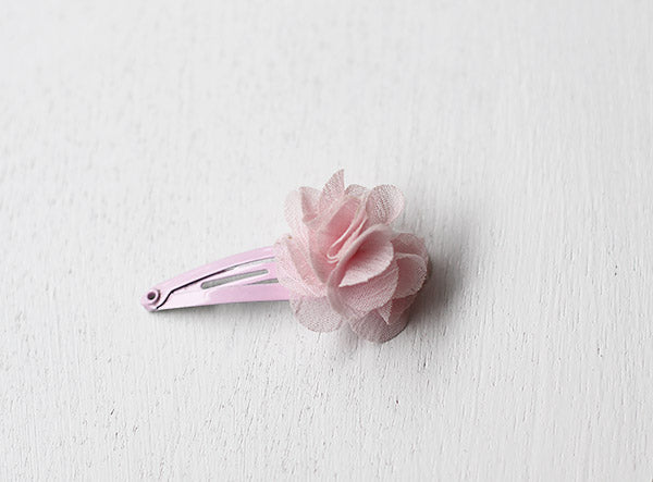 Pince cheveux bébé avec fleur rose en tissu. Parfait pour sublimer une coiffure d'enfant à l'occasion d'une cérémonie. Photo en gros plan de la pince cheveux.