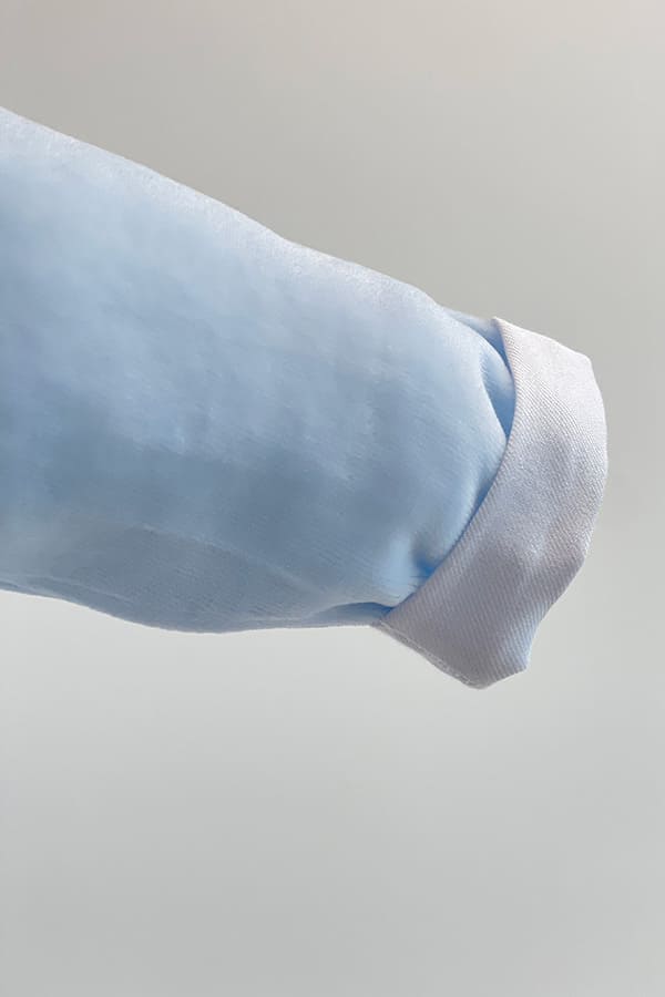 Gros plan sur la manche longue du pyjama bébé garçon Elio en velours de coton bleu ciel, terminée par un large revers blanc – Fil de Légende.