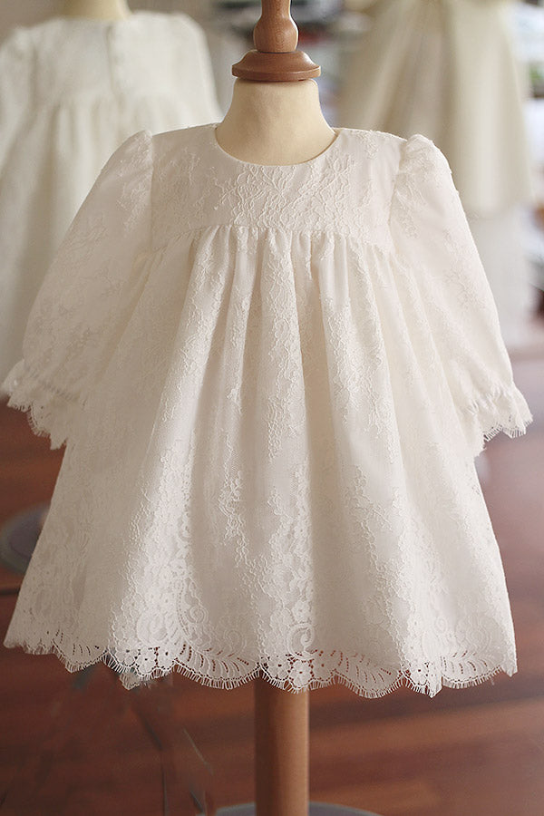 Robe de baptême ou de cérémonie pour bébé et petite fille en dentelle italienne, doublée de coton, modèle printemps à manches longues. Création Fil de Légende, disponible en ligne et en boutique à Paris–Neuilly-sur-Seine.