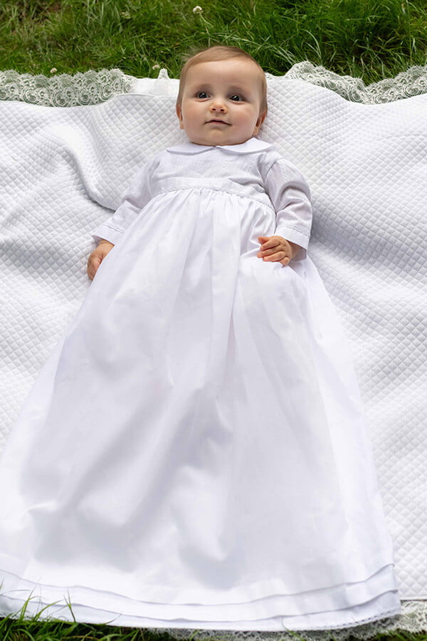 Robe traditionnelle mixte en coton blanc pour bébé fille et garçon. Corsage en coton brodé et dentelle de coton. Modèle manches longues. Création française Fil de Légende. Photo de la robe portée sur un bébé garçon.