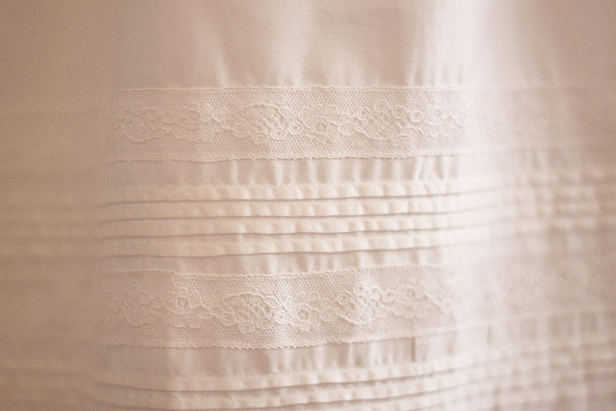 Robe baptême traditionnelle mixte pour bébé fille ou garçon en coton blanc et dentelle de Calais. Modèle manches longues. Création française Fil de Légende. Photo du gros plan des détails de la jupe.