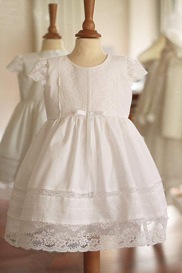 Robe de baptême pour bébé fille en coton blanc et dentelle de Calais, modèle été à manches courtes. Création française Fil de Légende, disponible en ligne et en boutique showroom à Paris–Neuilly-sur-Seine.