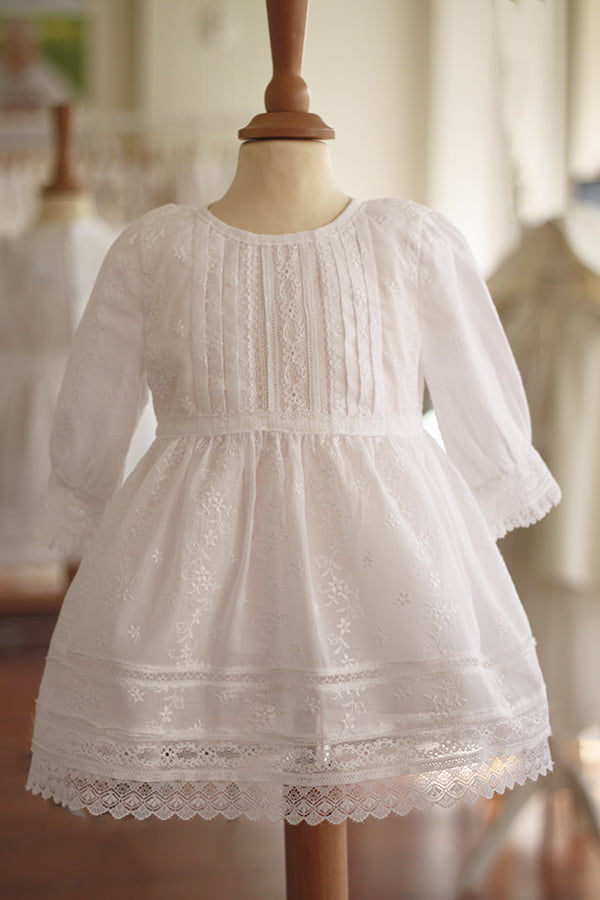 Robe de baptême et de cérémonie pour bébé fille, en broderie anglaise blanche et dentelle de Calais. Robe de baptême haut de gamme, création française Fil de Légende. Disponible en ligne ou en boutique showroom à Paris – Neuilly‑sur‑Seine.