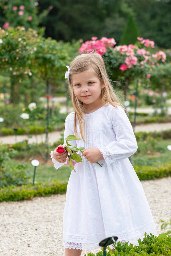 Robe de baptême et de cérémonie pour bébé fille, en broderie anglaise blanche et dentelle de Calais. Robe de baptême haut de gamme, création française Fil de Légende. Photo de la robe portée par une petite fille qui marche.