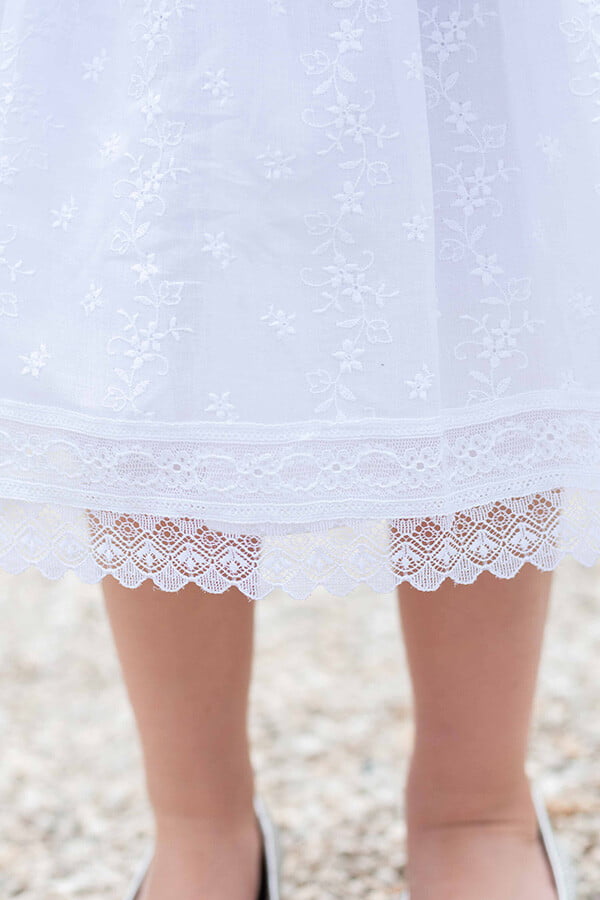 Robe de baptême et de cérémonie pour bébé fille, en broderie anglaise blanche et dentelle de Calais. Robe de baptême haut de gamme, création française Fil de Légende. Photo de la dentelle de la jupe.