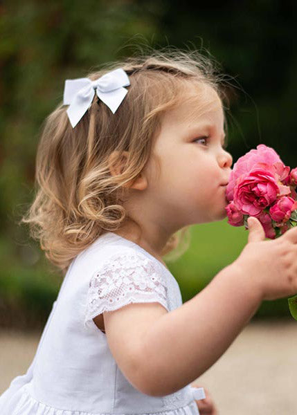 Pince cheveux noeud en gros grain blanc pour petite fille. Parfait pour sublimer une robe de cérémonie pour enfant. Photo de la barrette portée par une petite fille.