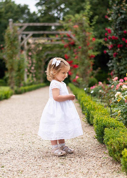 Pince cheveux noeud en gros grain blanc pour petite fille. Parfait pour sublimer une robe de cérémonie pour enfant. Photo de la barrette portée avec une robe de cérémonie.