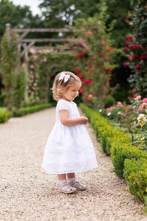 Robe de baptême pour bébé fille en coton blanc et dentelle de Calais, modèle été à manches courtes. Création française Fil de Légende. Photo de robe vue de côté.