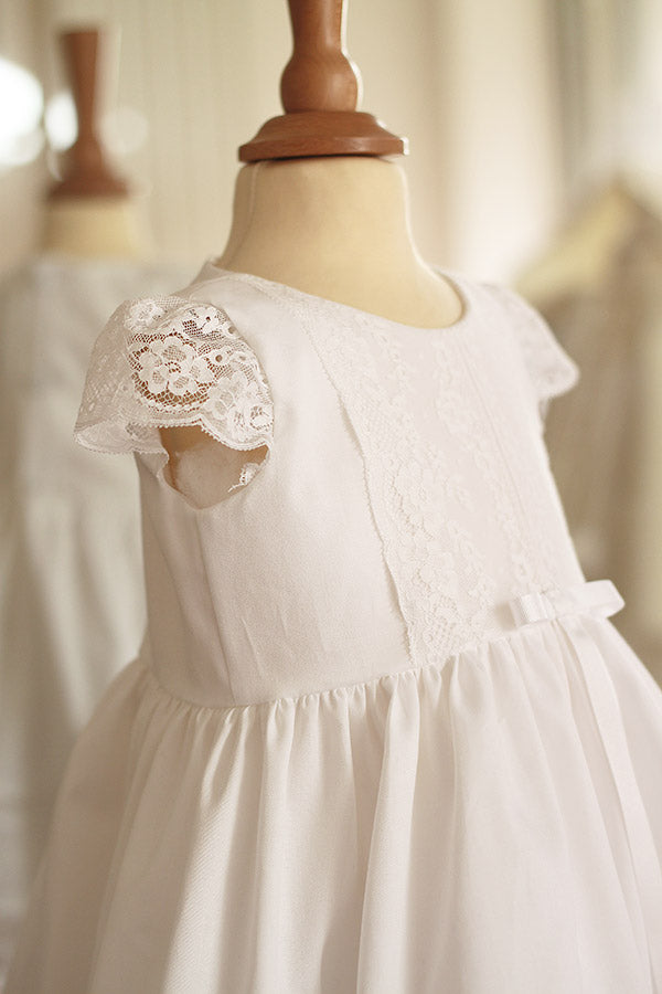 Robe de baptême pour bébé fille en coton blanc et dentelle de Calais, modèle été à manches courtes. Création française Fil de Légende. Photo sur mannequin de couture.