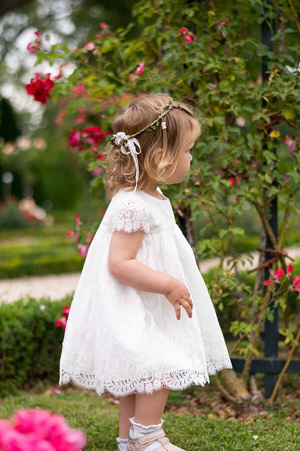Robe de baptême ou de cérémonie pour bébé et petite fille en dentelle italienne, doublée de coton, modèle été à manches courtes. Création Fil de Légende. Photo de la robe portée par une petite fille.