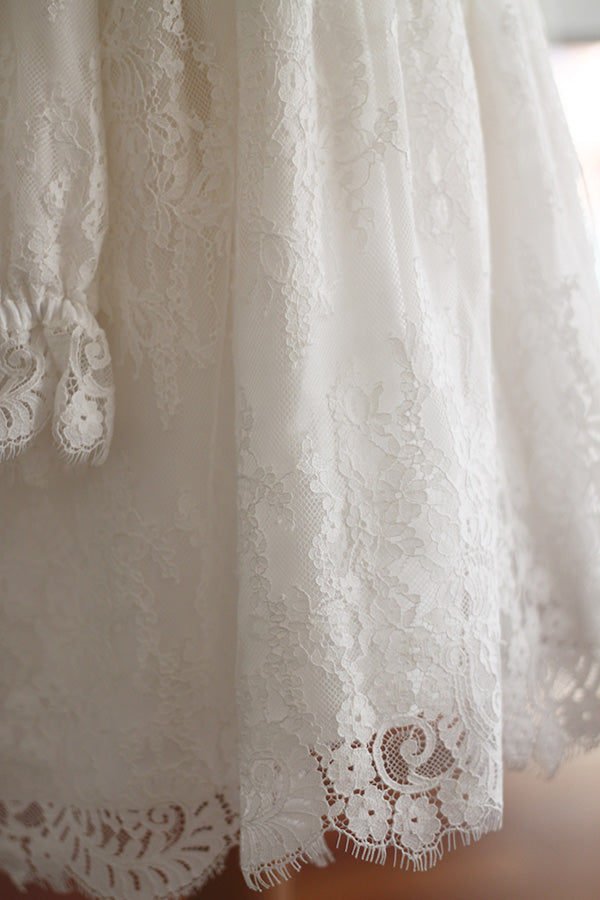 Robe de baptême fille taille haute en dentelle italienne blanc cassé doublée polaire. Modèle chaud pour l'hiver avec manches longues. Création française Fil de Légende. Photo gros plan sur la dentelle.