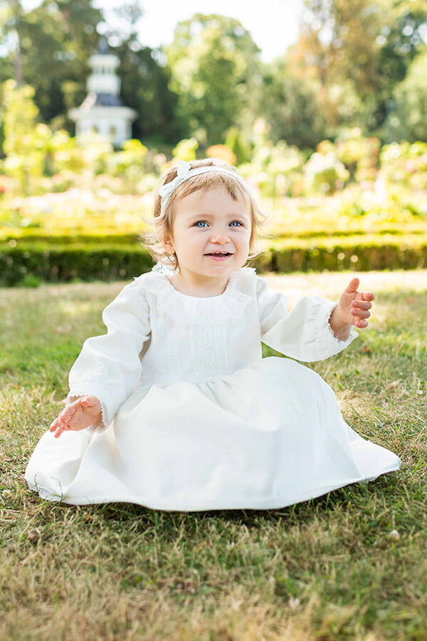 Robe de baptême fille pour l'hiver en velours blanc cassé et dentelle de Calais, doublée polaire. Création française Fil de Légende. Photo du devant de la robe.