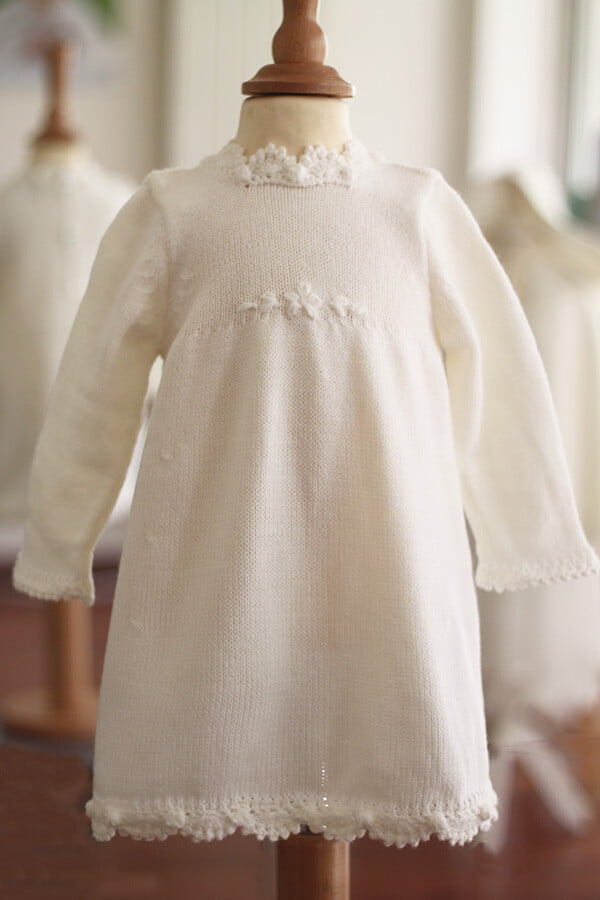 Robe baptême fille blanc cassé en maille tricotée avec bordures faites au crochet à la main. Robe en lainage. Création française Fil de Légende. Disponible en ligne ou en boutique showroom à Paris, Neuilly-sur-Seine.