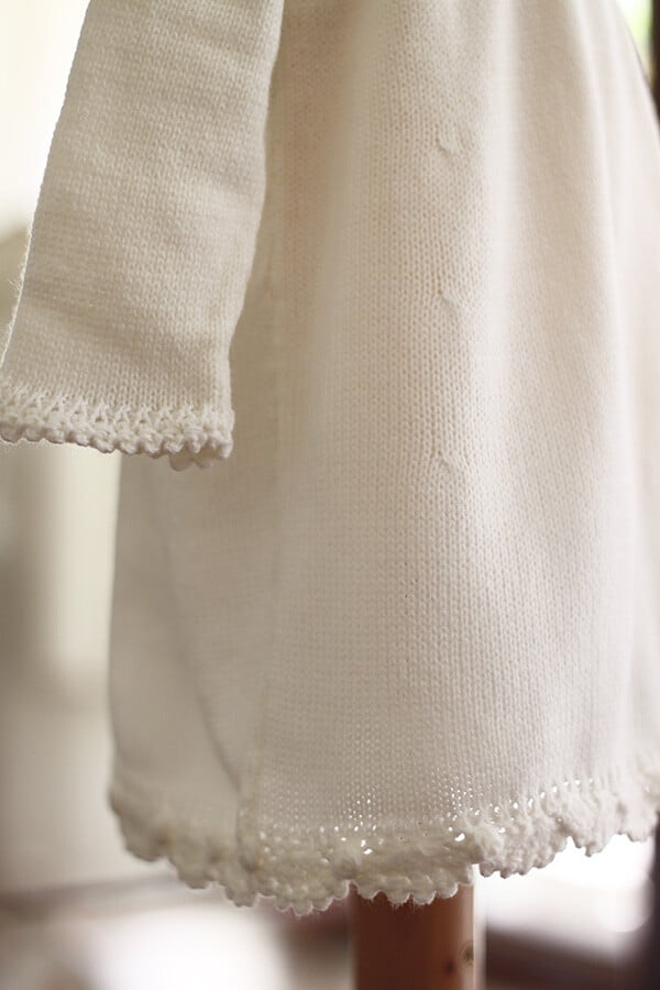 Robe baptême fille blanc cassé en maille tricotée avec bordures faites au crochet à la main. Robe en lainage. Création française Fil de Légende. Photo de la bordure des manches.