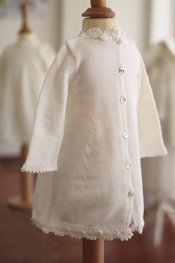 Robe baptême fille blanc cassé en maille tricotée avec bordures faites au crochet à la main. Robe en lainage. Création française Fil de Légende. Photo du dos de la robe.