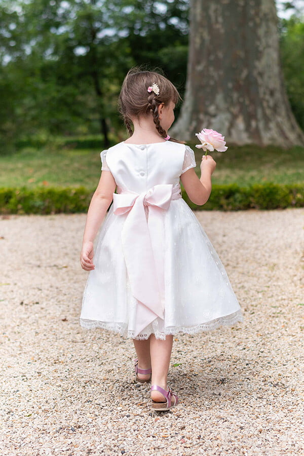 Robe de baptême ou de cérémonie pour bébé et petite fille en dentelle de Calais, doublée de satin, modèle été à manches courtes. Création Fil de Légende. Photo de robe portée par une petite fille de dos.
