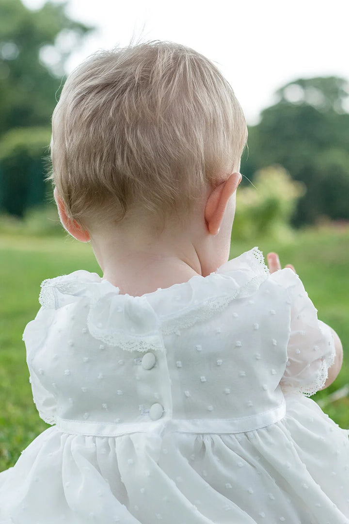 Robe de baptême bébé fille en voile plumetis doublé coton. Modèle été manches courtes. Création française Fil de Légende. Photo du dos de la robe.
