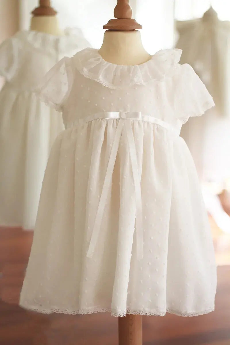Robe de baptême bébé fille en voile plumetis doublé coton. Modèle été manches courtes. Création française Fil de Légende. Disponible en ligne ou en boutique showroom à Paris-Neuilly-sur-Seine.