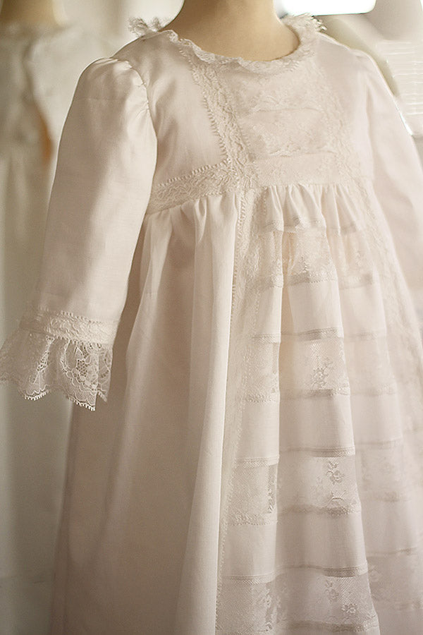 Robe de baptême traditionnelle bébé en coton et dentelle de Calais blanc cassé. Modèle manches longues. Création française Fil de Légende. Photo de la robe vue de côté.