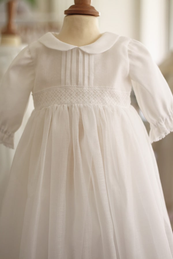 Robe de baptême longue traditionnelle mixte pour filles et garçons en mousseline et dentelle fine. Modèle manches longues. Création française Fil de Légende.  Photo de la robe sur mannequin de couture.