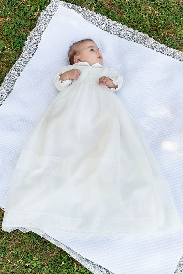 Robe de baptême longue traditionnelle mixte pour filles et garçons en mousseline et dentelle fine. Modèle manches longues. Création française Fil de Légende.  Photo de la robe portée par un bébé fille.